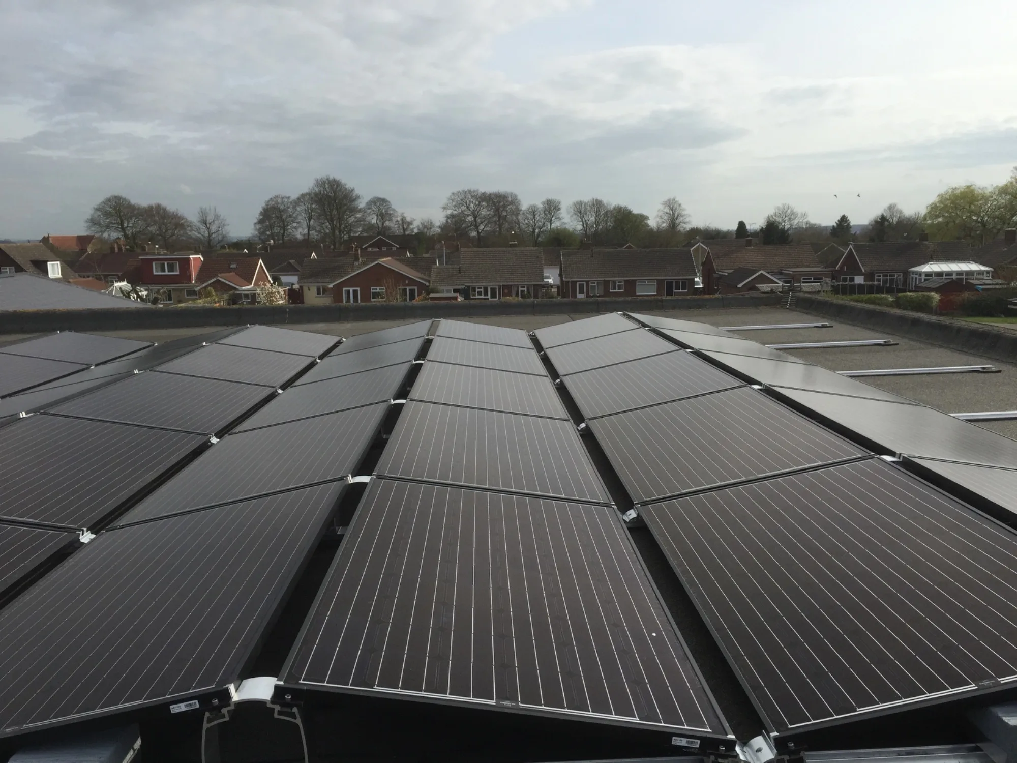 Black solar panels across a flat roof overlooking rooftops