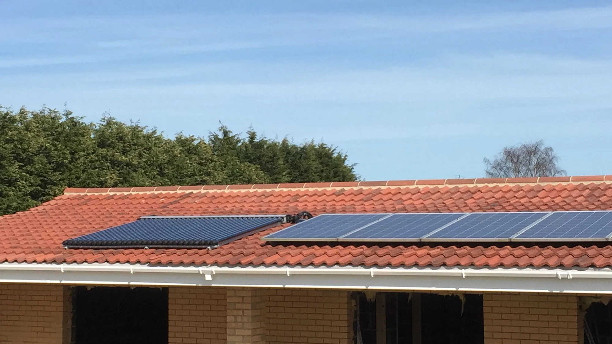 Solar PV panels fitted alongside a solar thermal collector on a new-build roof